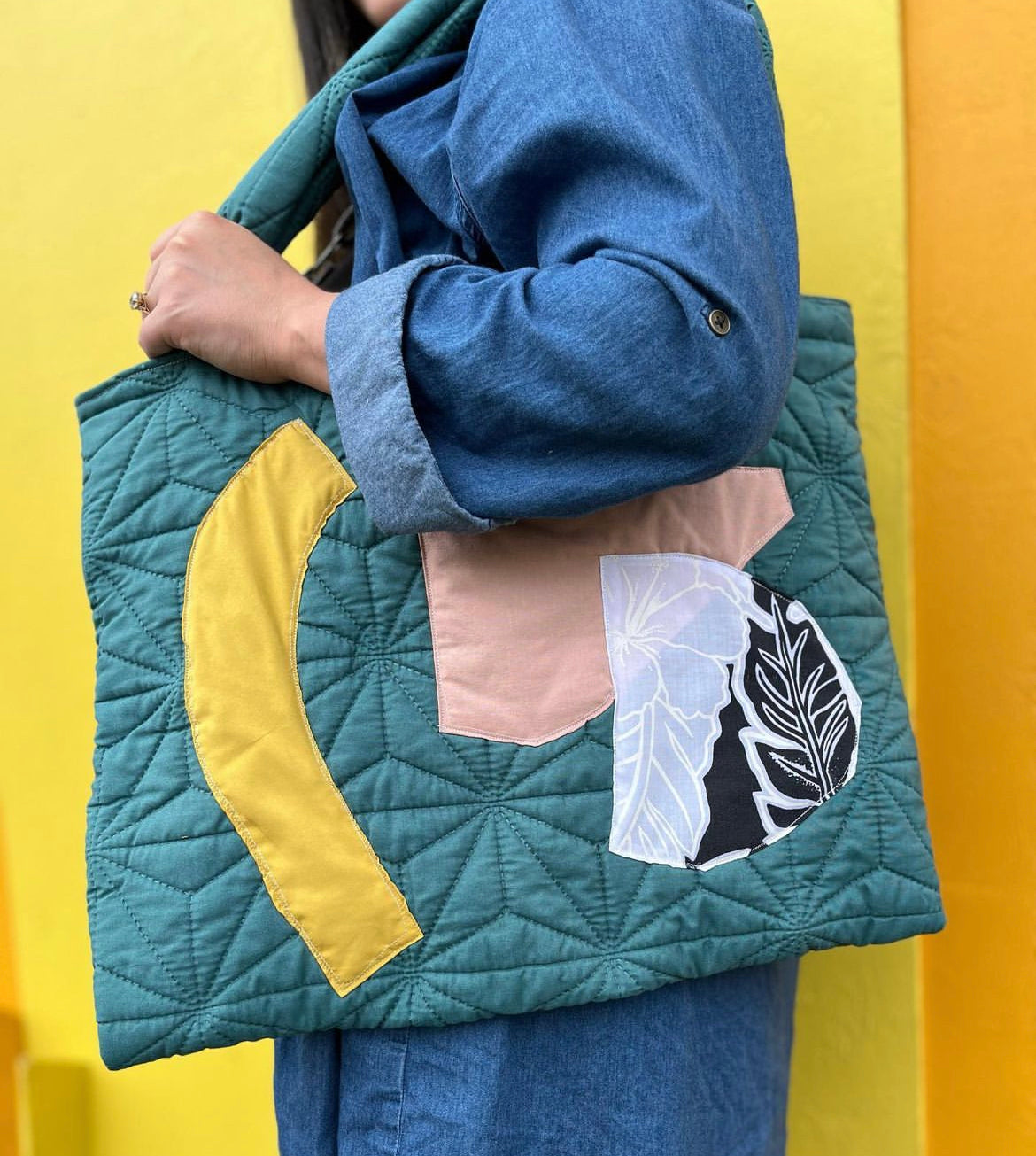 A person holding a colorful tote bag on her shoulder